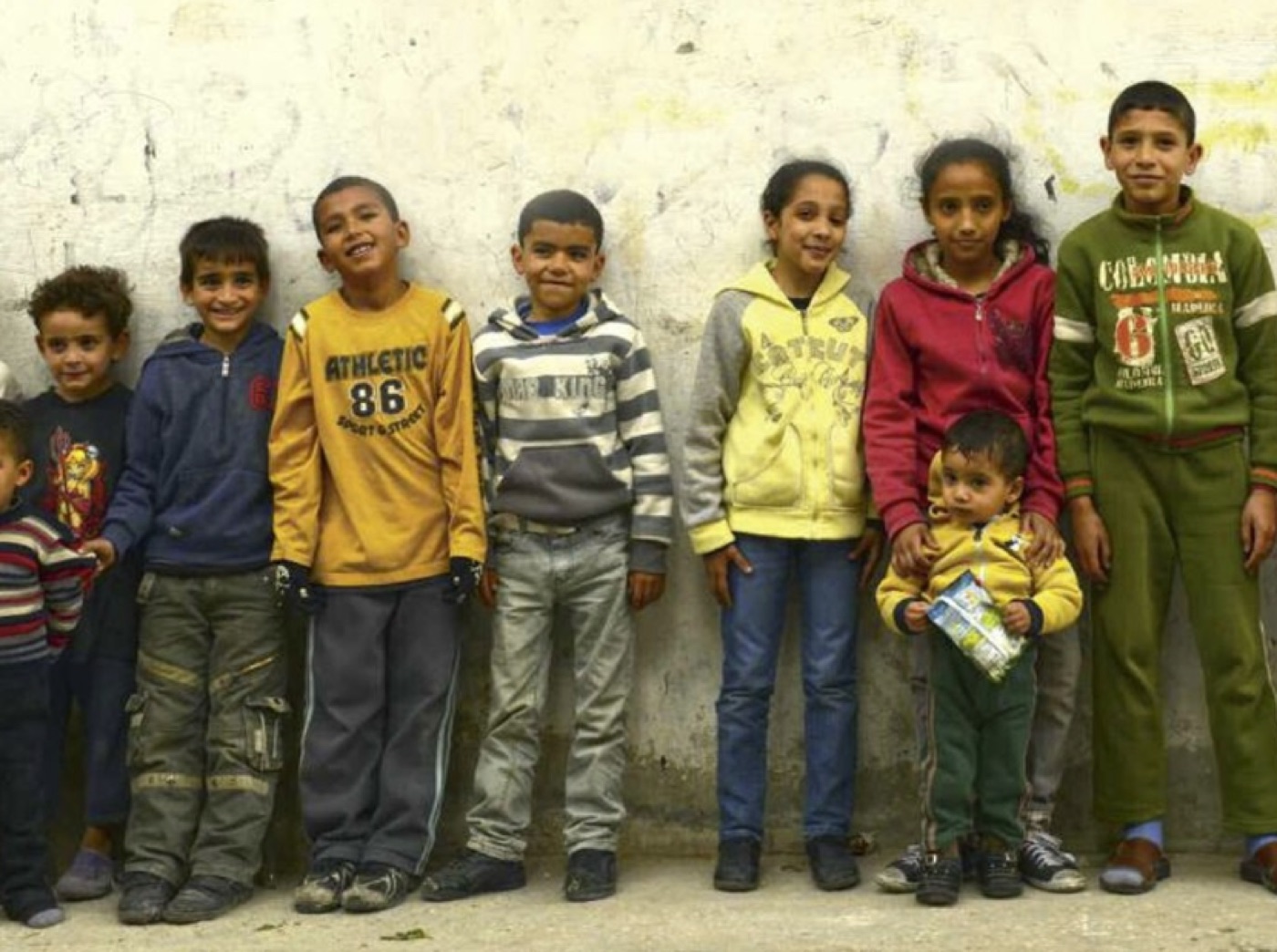 Ni barn står oppstilt mot en murvegg i Nablus.